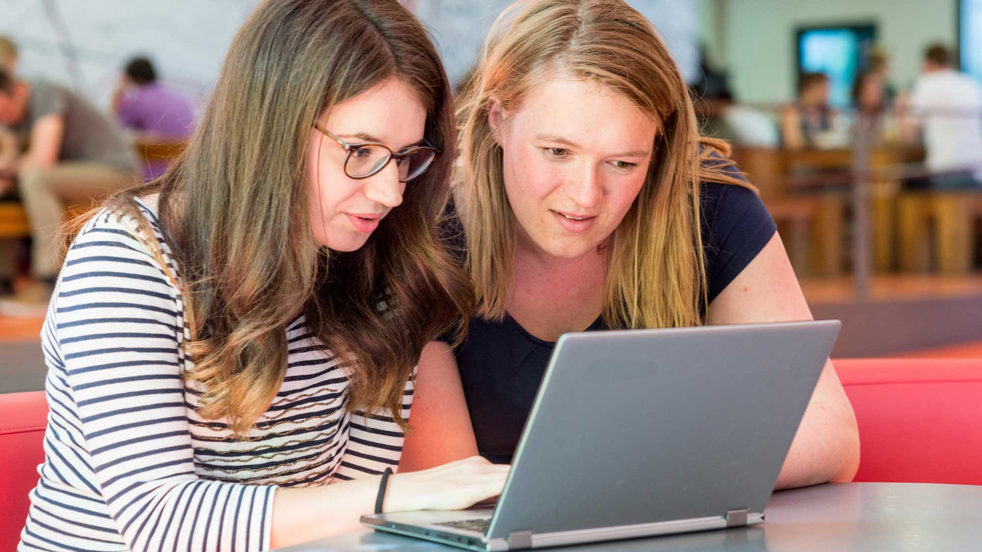 Zwei Frauen schauen auf einen Laptop