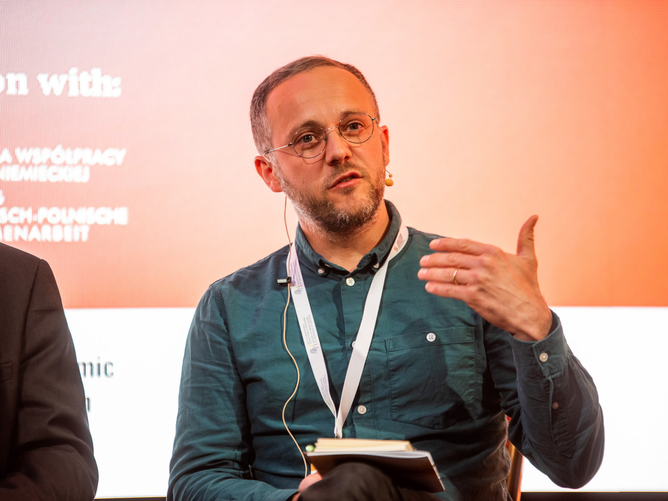 Eduard Klein, wearing a blue shirt, gives a talk on stage at a conference.