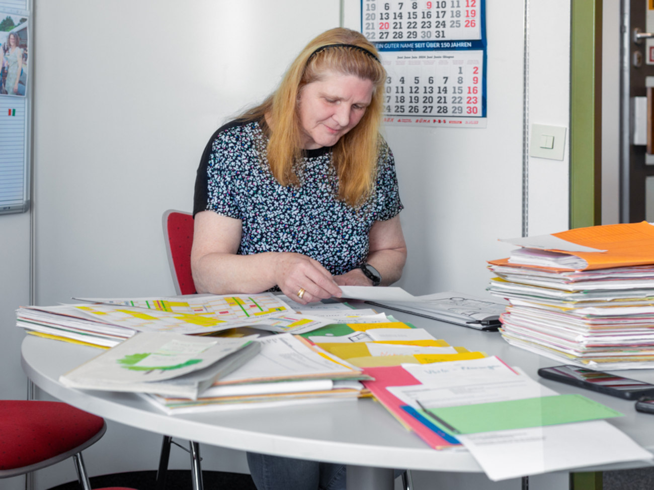 Heike Hemmersbach sits at her desk among lots of paperwork.