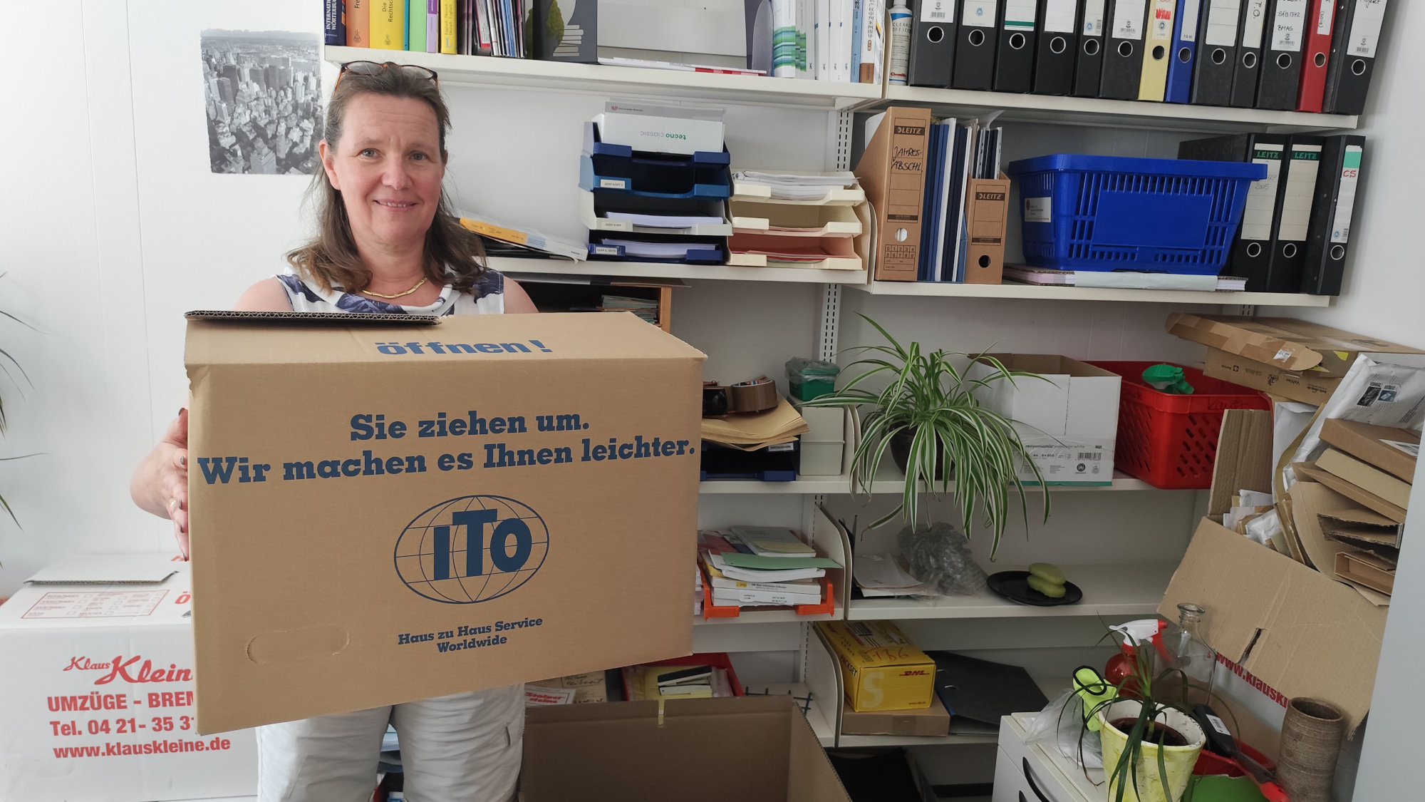 Antje Kautz steht in einem Büro und hält einen Umzugskarton in den Händen.