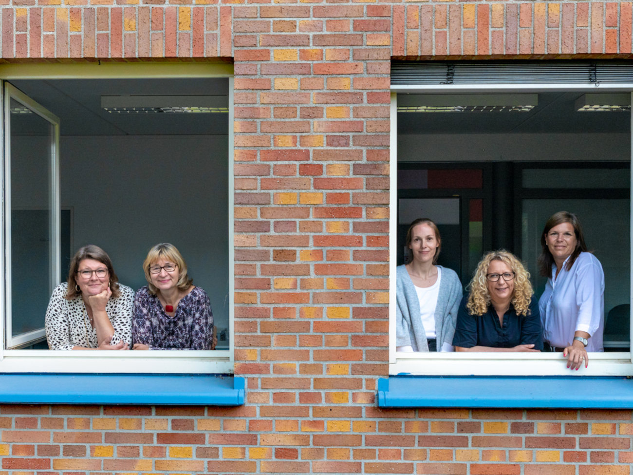 Fünf Frauen von HERE AHEAD stehen am Fenster