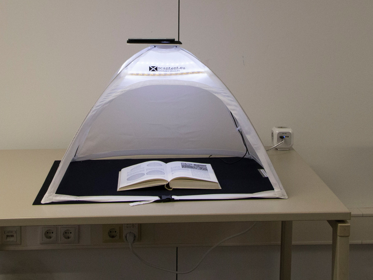 Ein kleines Zelt, in dem ein Buch abfotografiert wird.