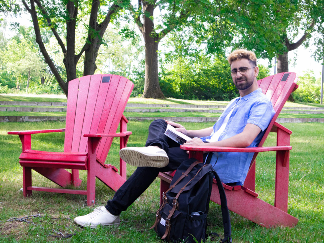 Zakir sits on one of the red Dickinson chairs on the university lawn.