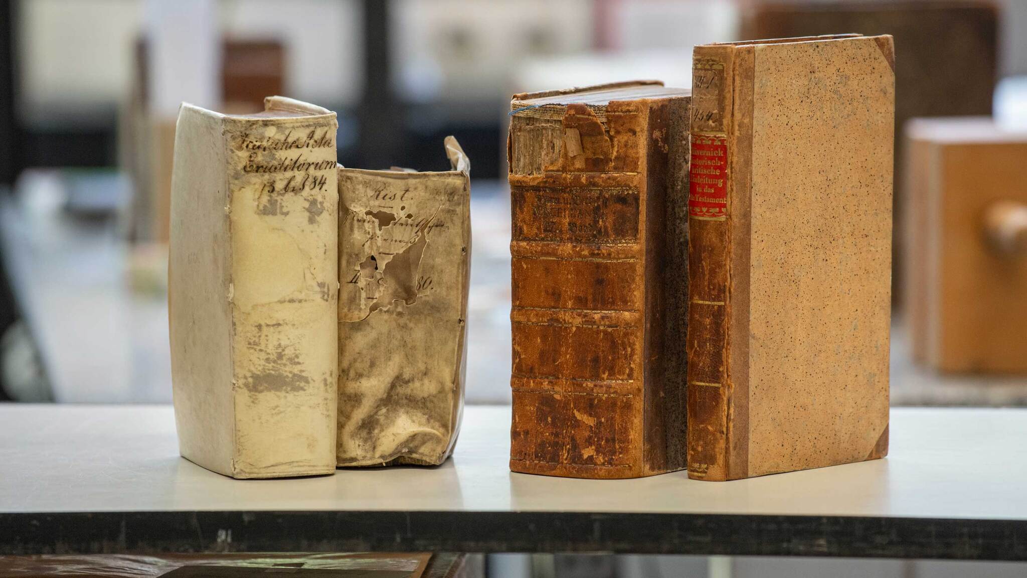 Four old books are lined up on a table.