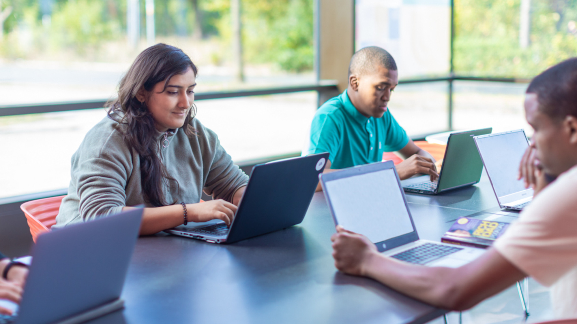 Students sitting in front of their laptops in the MZH building and study.