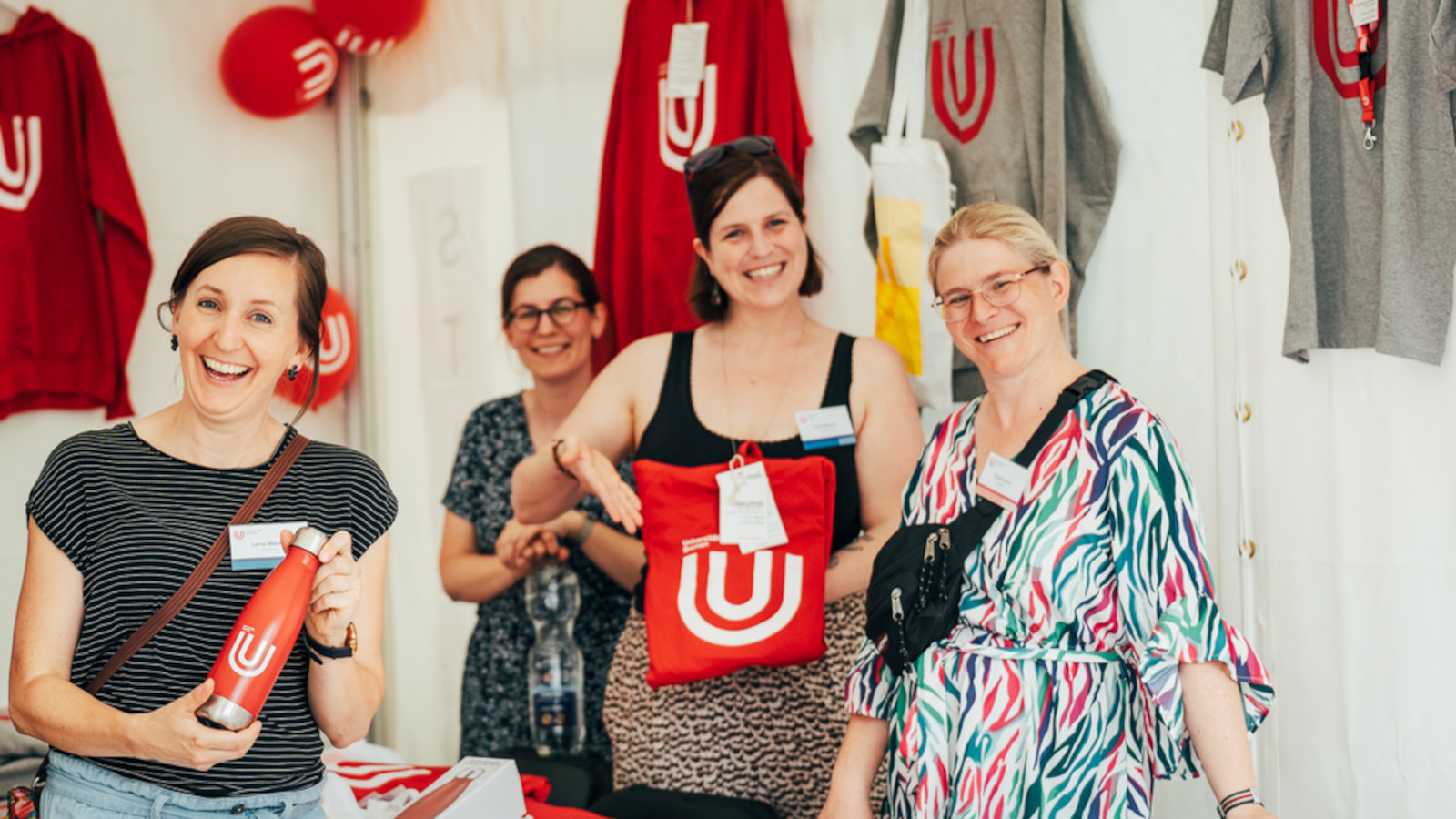 Members of the team of the University Communication and Marketing Unit (KOMMA) holding merch of the University of Bremen in their hands