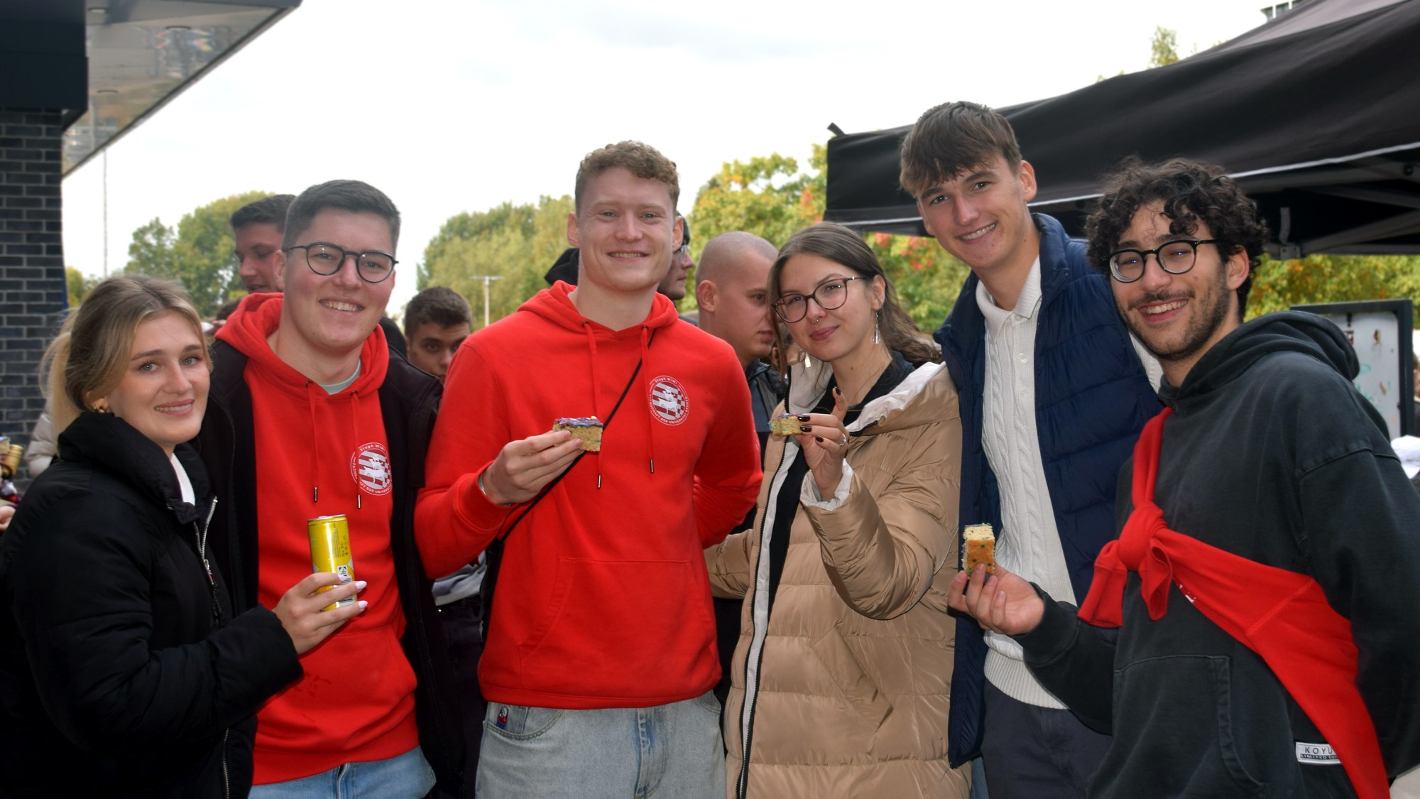 Eine Gruppe von sechs Menschen steht zusammen und lächelt in die Kamera.