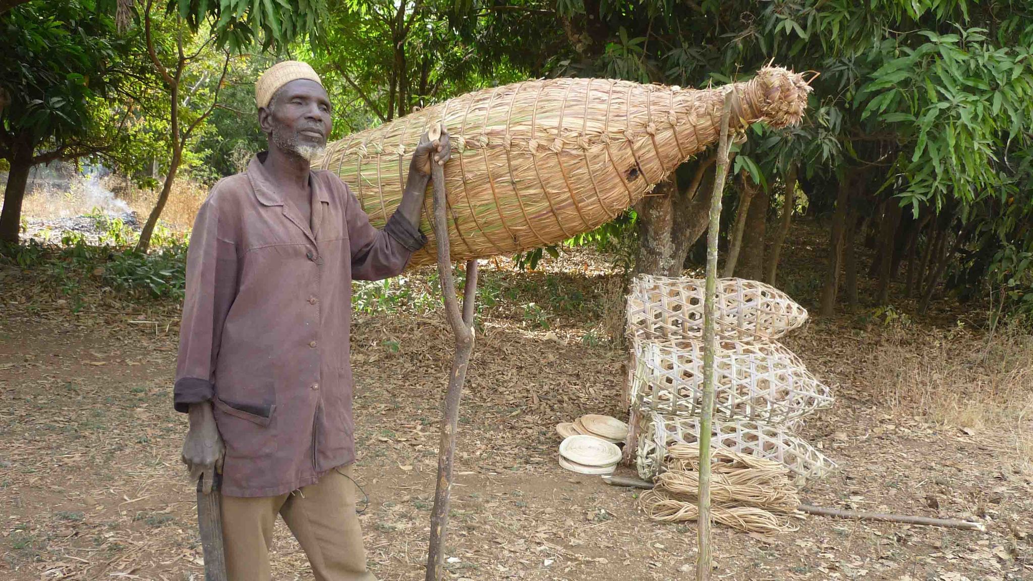 Beehives are artfully crafted by hand in Cameroon. The photo shows a Cameroonian beekeeper. It is the cover photo of the book by Martin Gruber and Mazi Sanda.