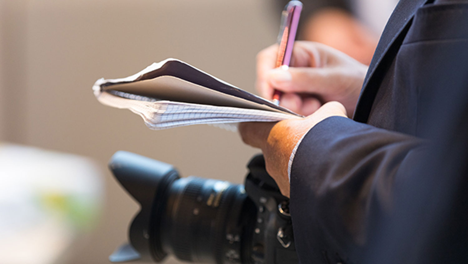 Journalist mit Stift und Papier und einer Kamera.