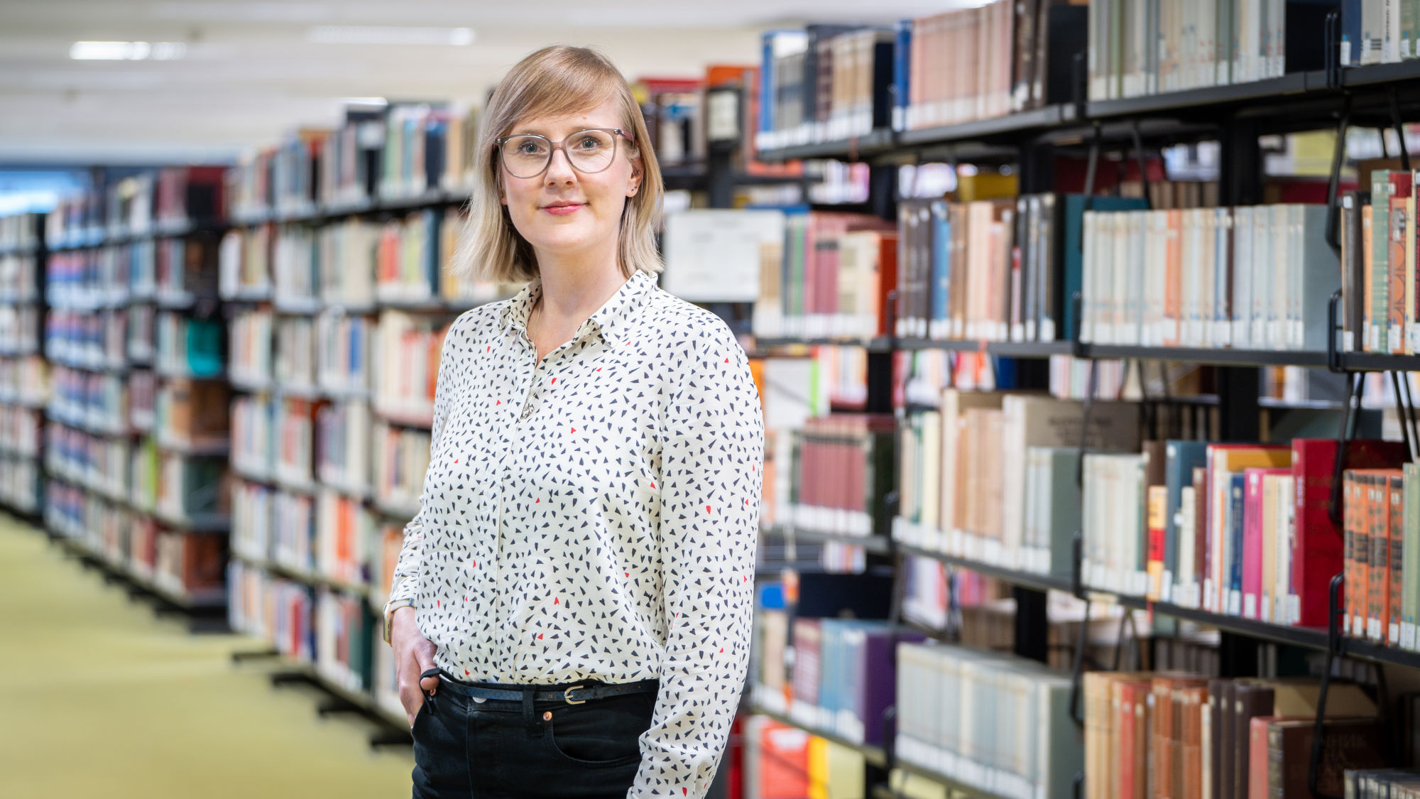 Stefanie Jakobi steht vor einem Bücherregal in der SuUB