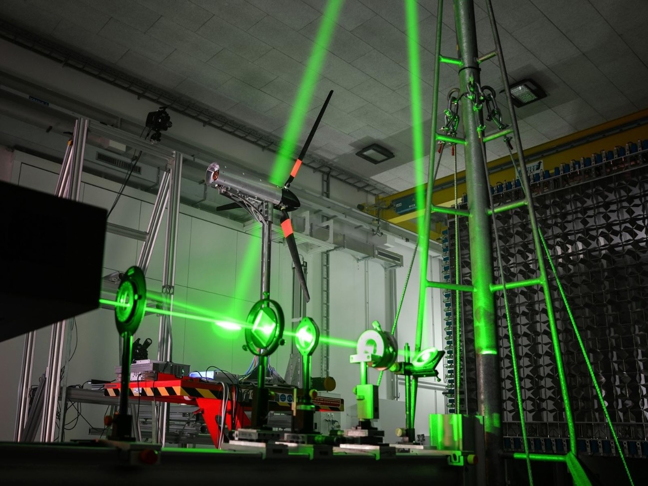 The picture shows a laser system in a measurement room, where green streaks of light can be seen.
