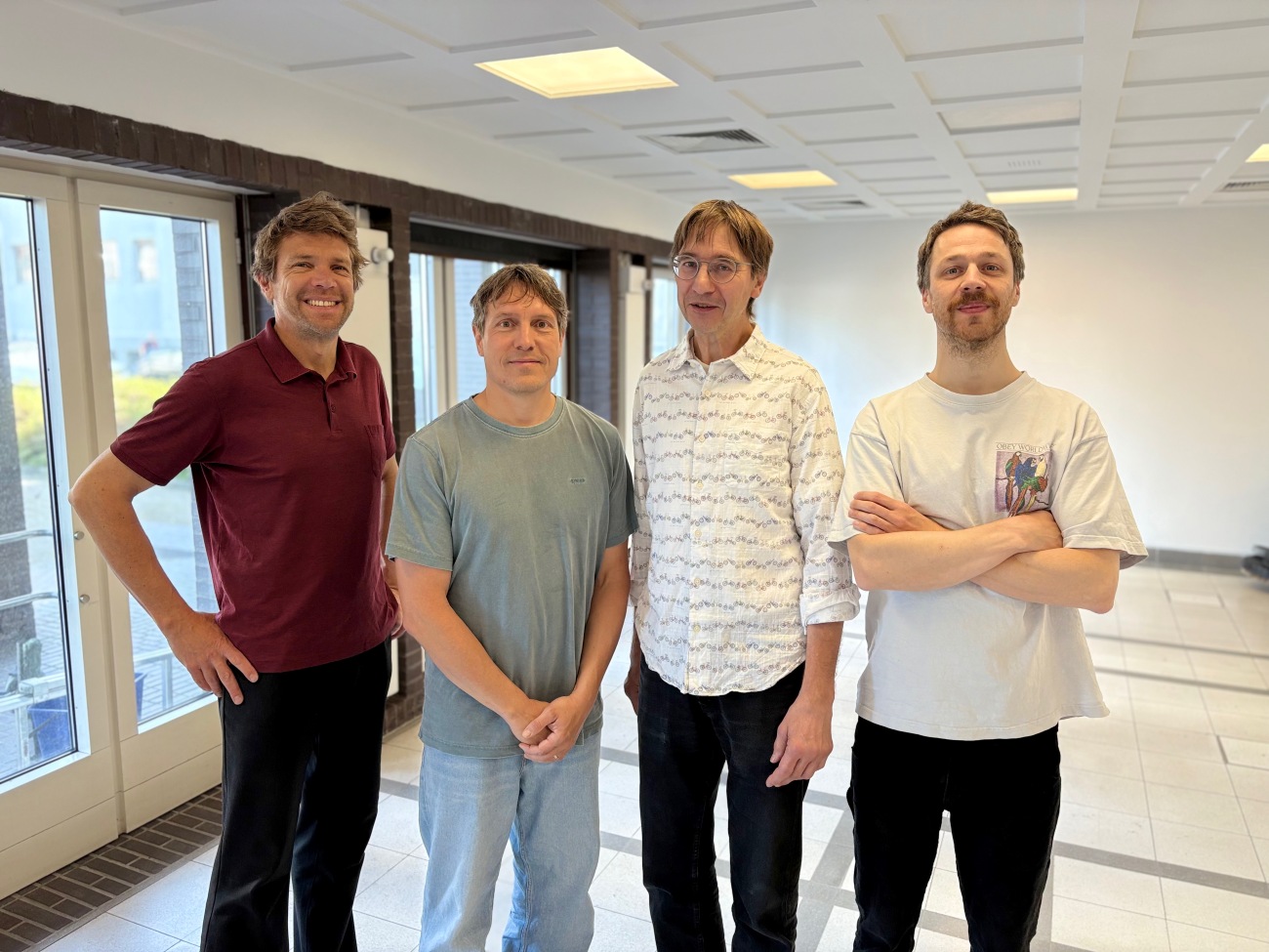 Four researchers standing side by side and smiling at the camera for a group photo.