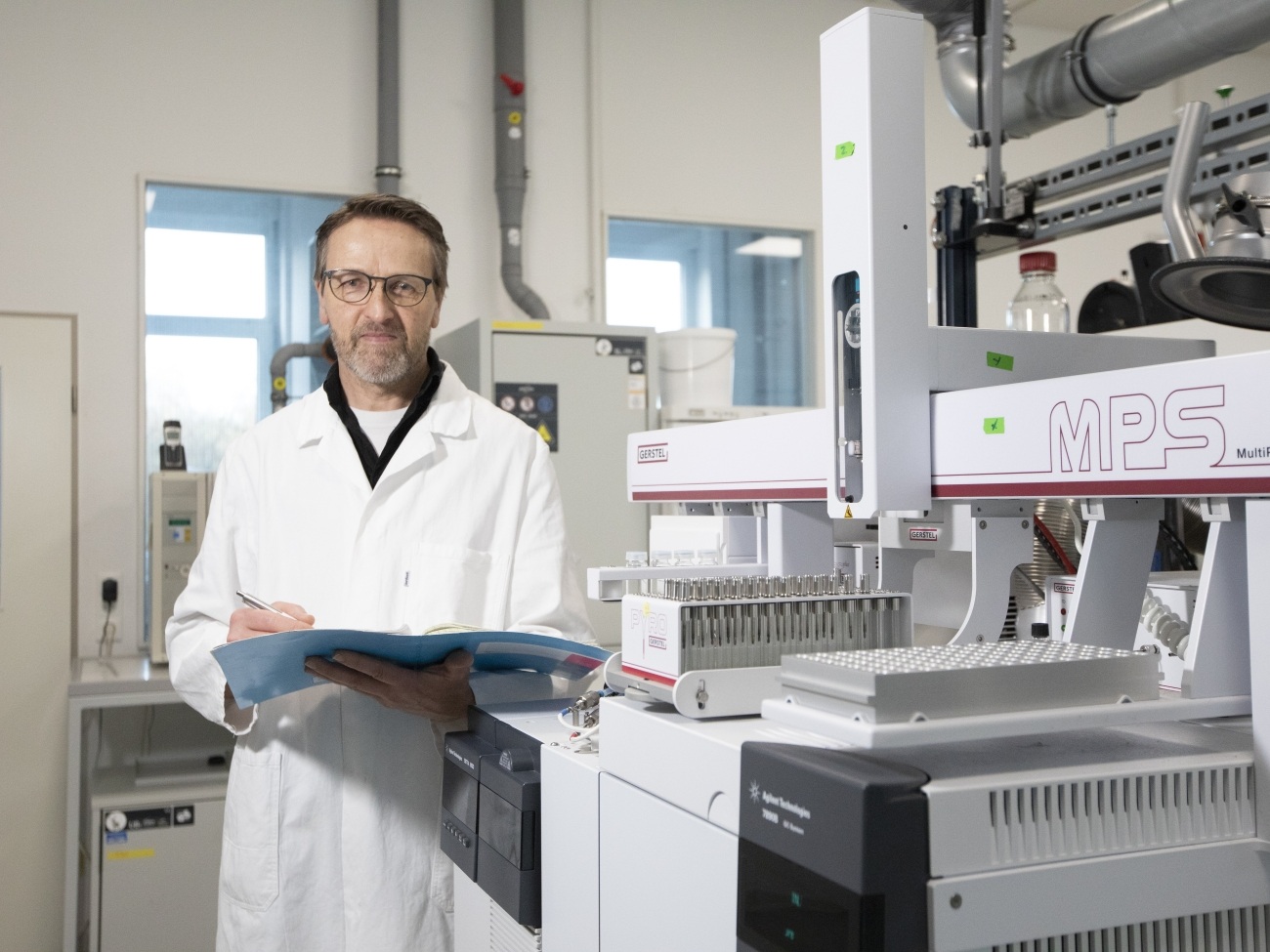 A person wearing a lab coat is standing in front of a table with many samples.