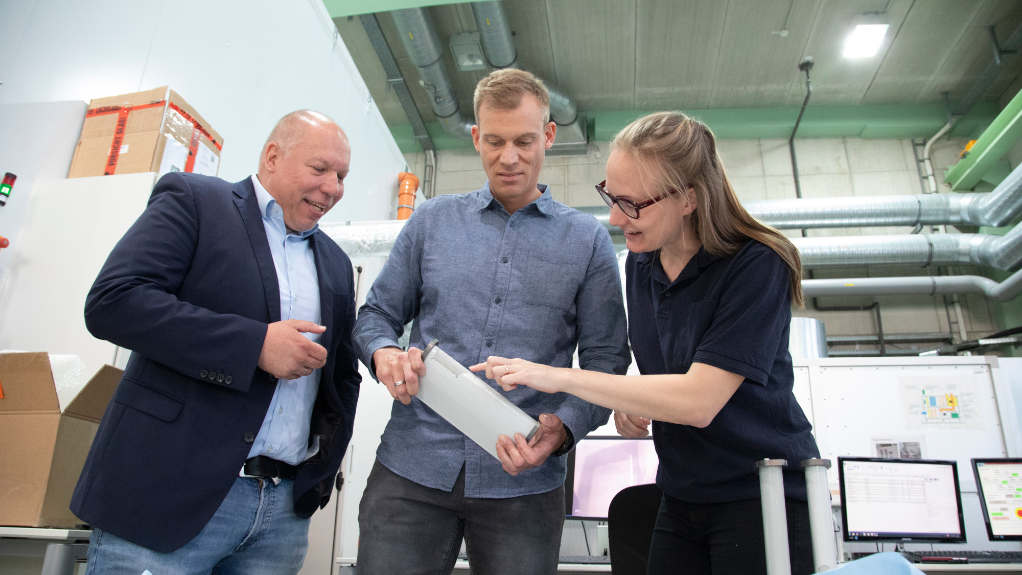 Sascha Buchbach, Stefan Krause und Cate Lester begutachten einen Prüfkörper.