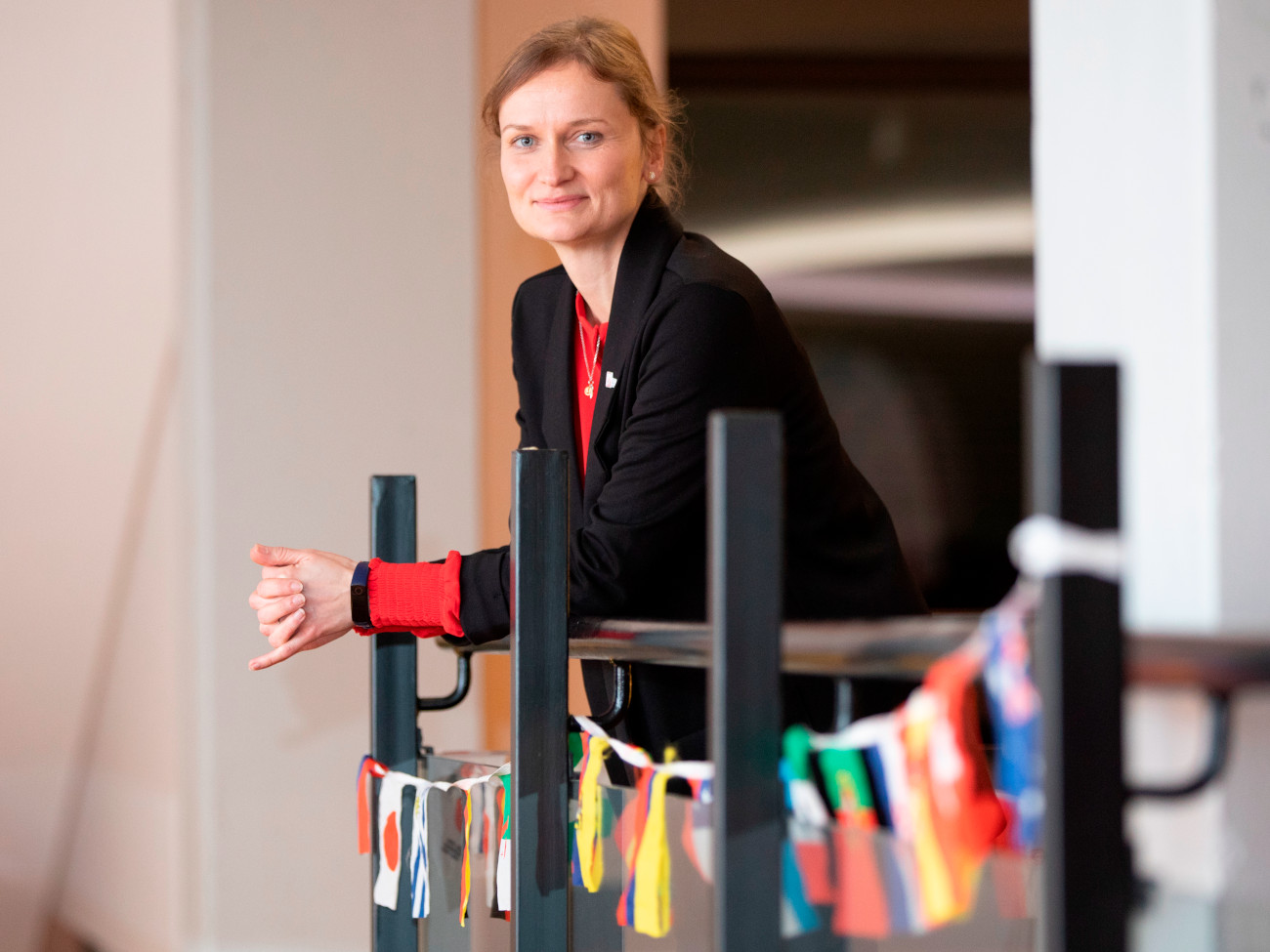 Julia Holz leans against a railing on which various national flags are displayed.