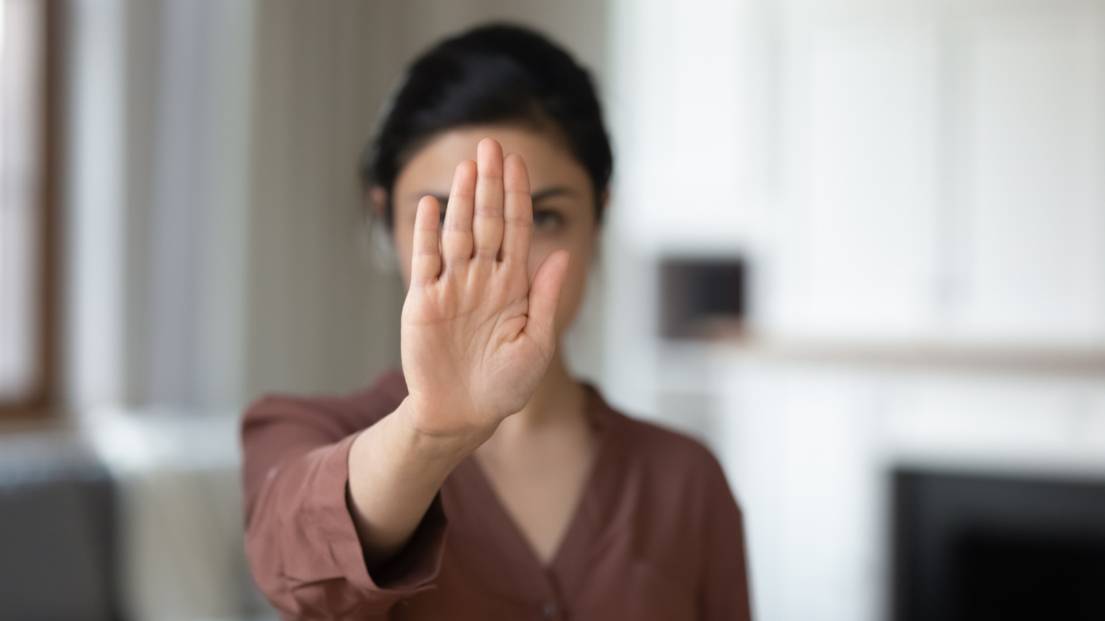 Frau hält flache Hand ausgestreckt vor ihrem Gesicht