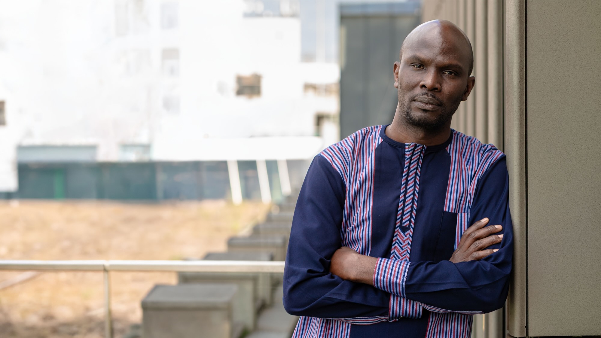 Dr. Mazi Sander is leaning against a wall on a rooftop terrace and looking into the camera.