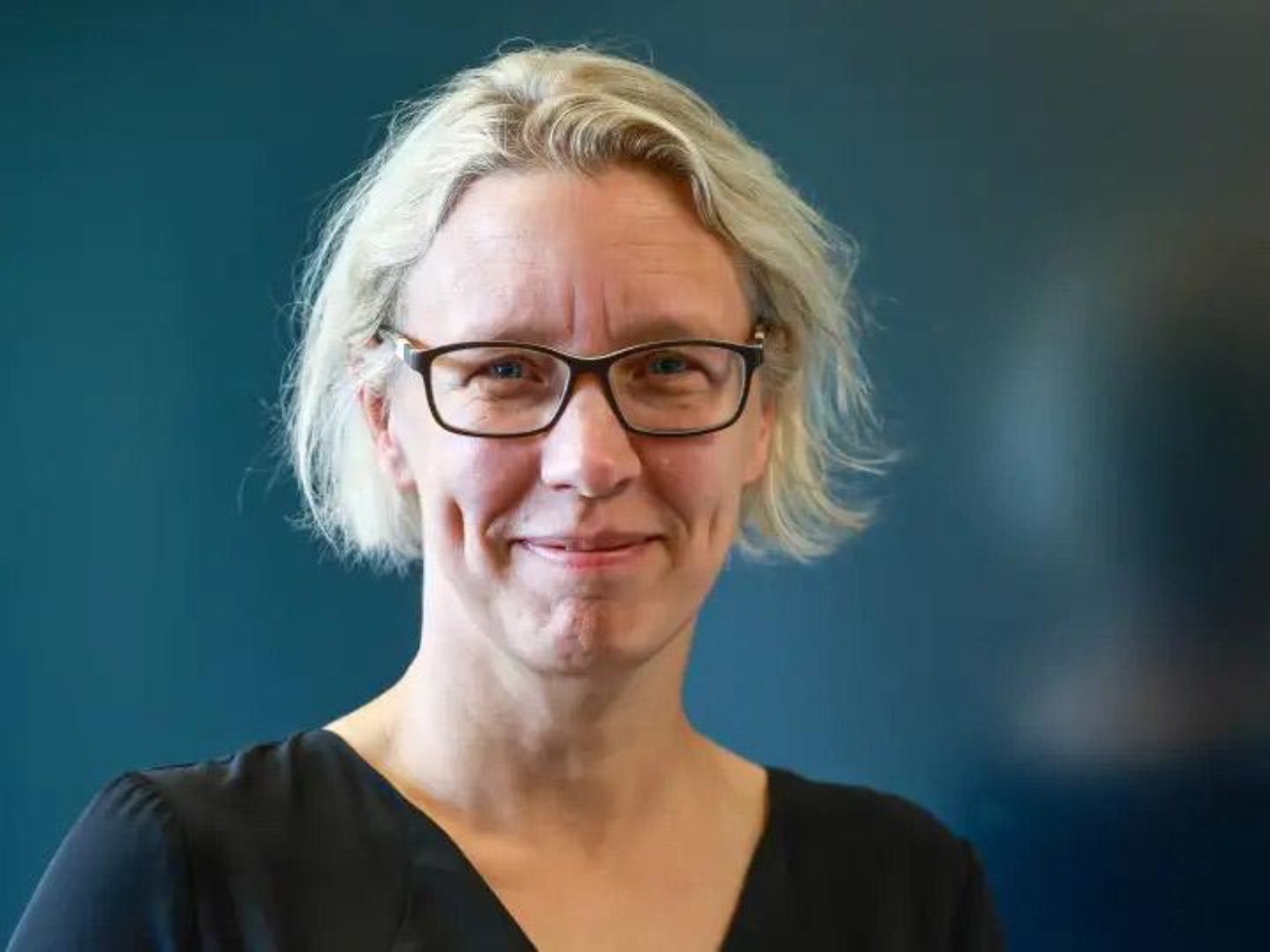 A portrait of Kerstin Radde-Antweiler against a dark blue background.