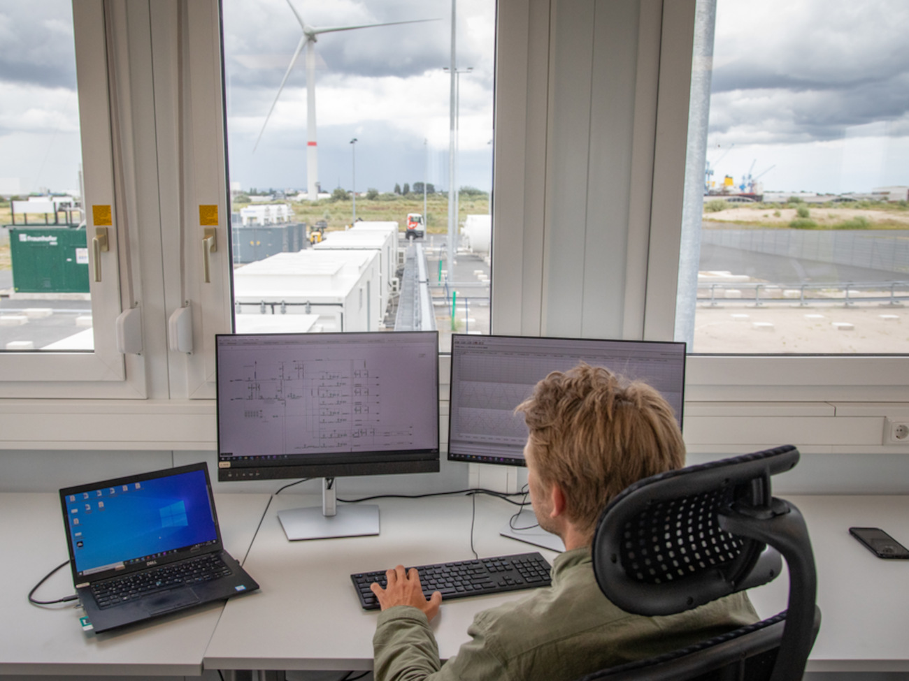 Jannes Vervoort sitzt vor zwei PC-Bildschirmen und einem Laptop in der Leitwarte des Hydrogen Lab Bremerhaven