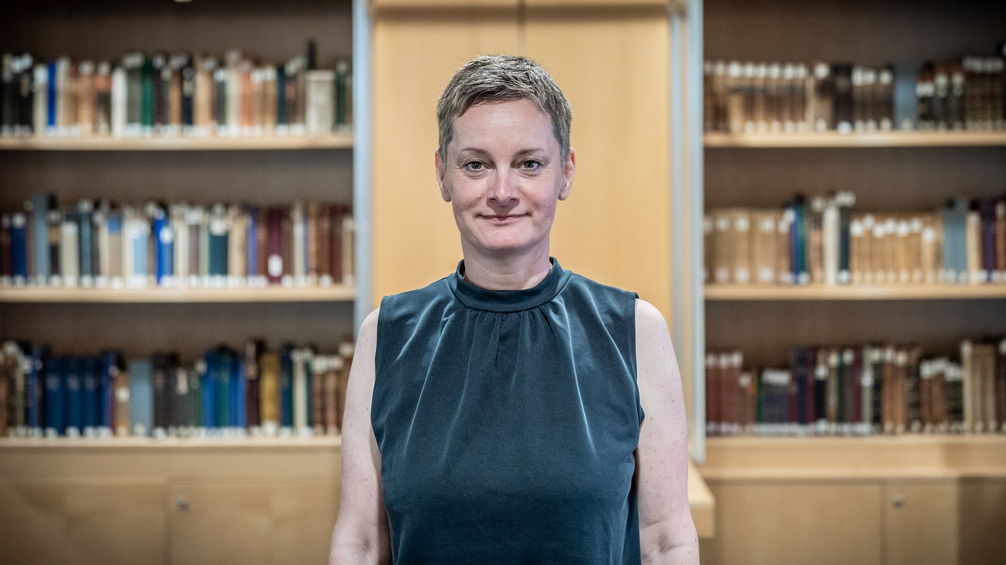 A portrait photo of PD Dr. Barbara Aehnlich in front of a bookshelf.