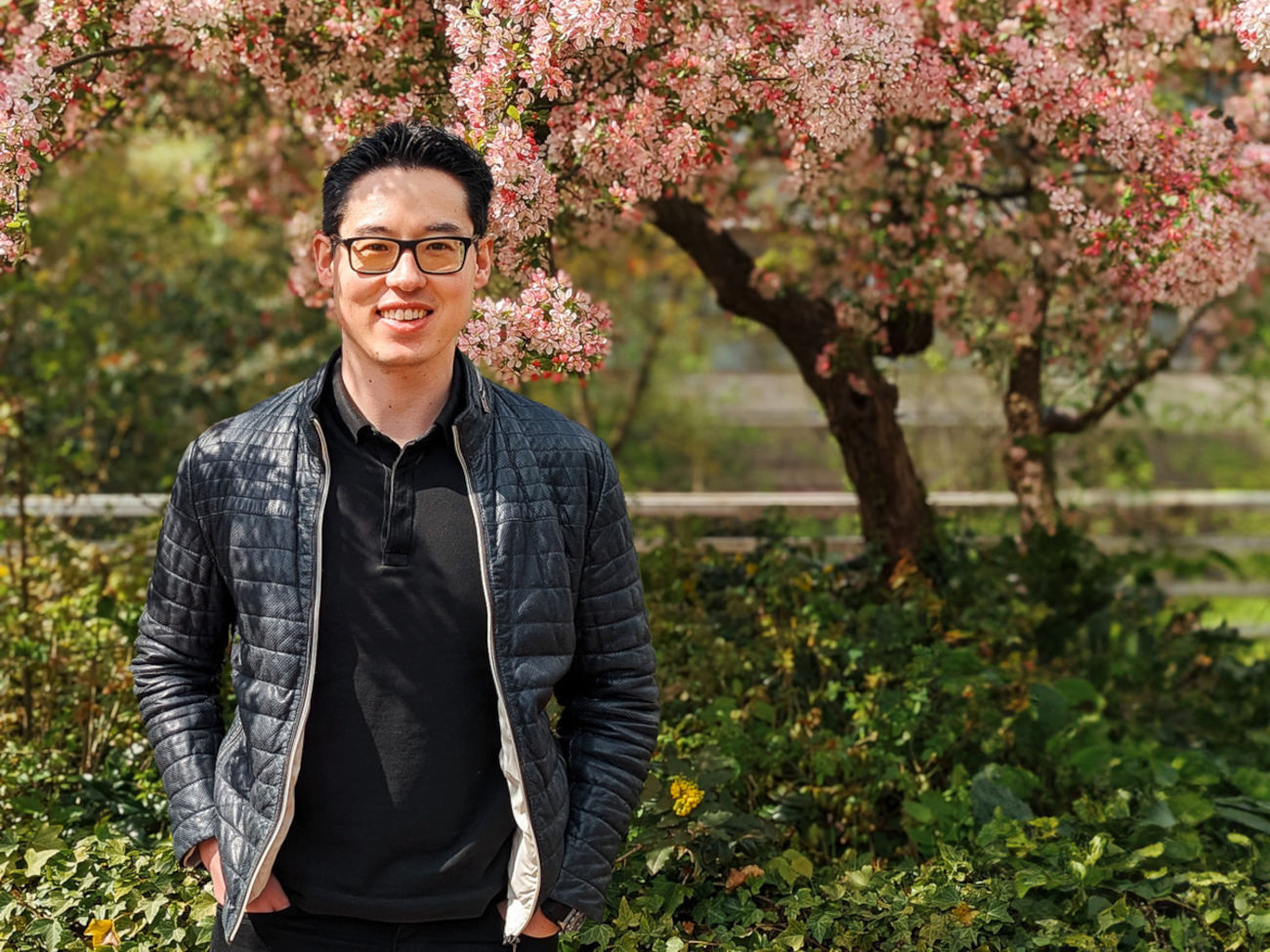 Prof. Dr. Dennis-Kenji Kipker is seen standing in front of a pink cherry blossom tree on the University of Bremen campus. He is a professor of IT security law.