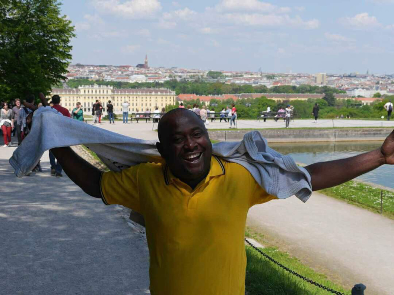 Der Künstler Recaredo Silebo Boturu lacht in die Kamera. Hinter ihm ist eine Stadt zu sehen.