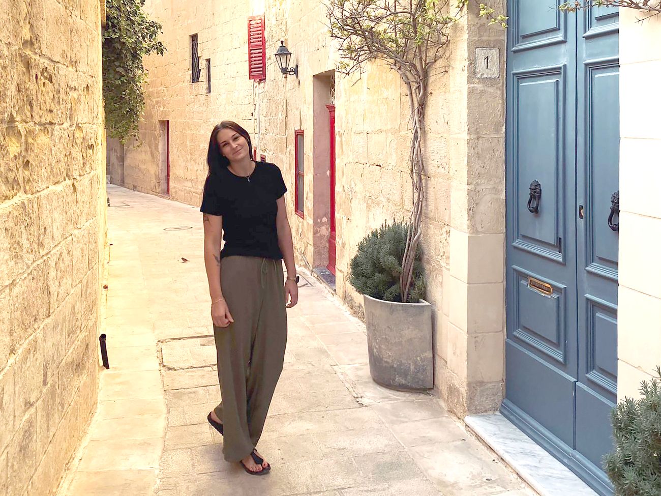 A woman stands in an old town area in Malta.