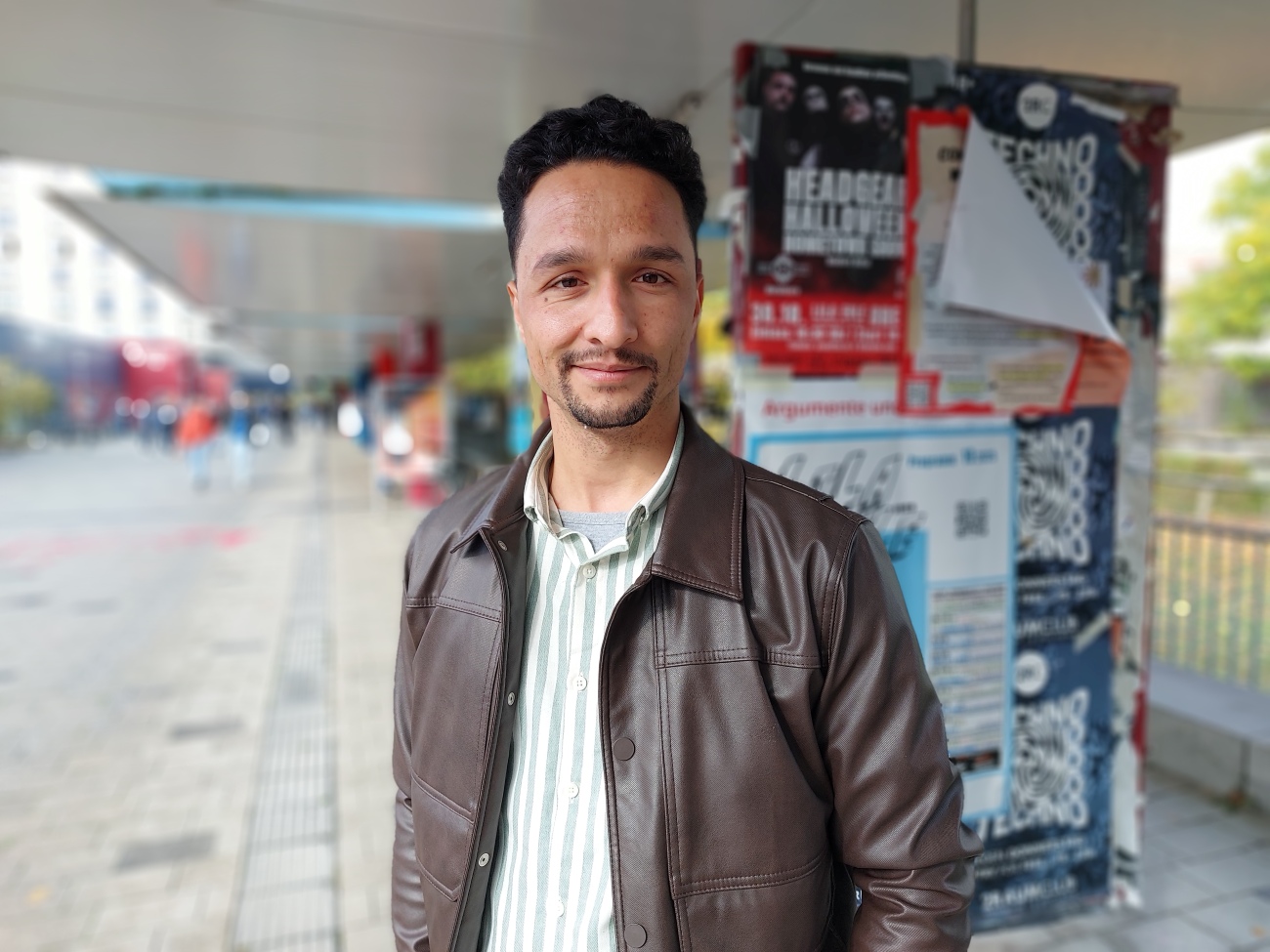 A man is standing on the boulevard and is looking at the camera.