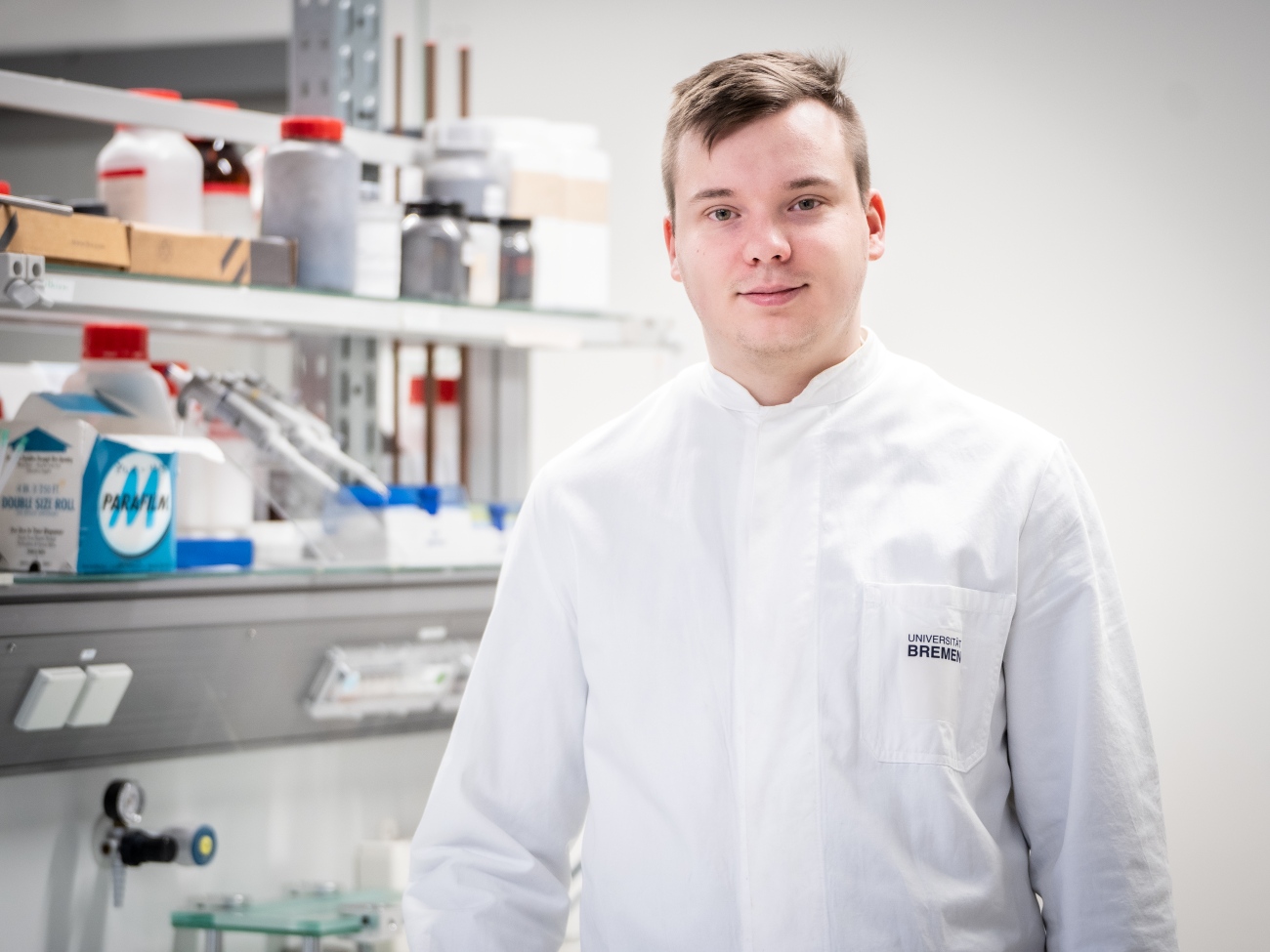 Student standing in front of a shelf in the laboratory.