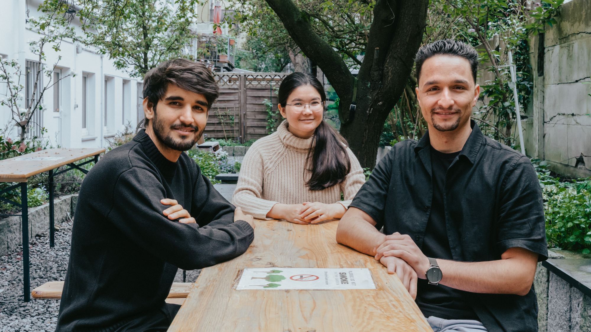 Three people are sitting at a table and looking at the camera.