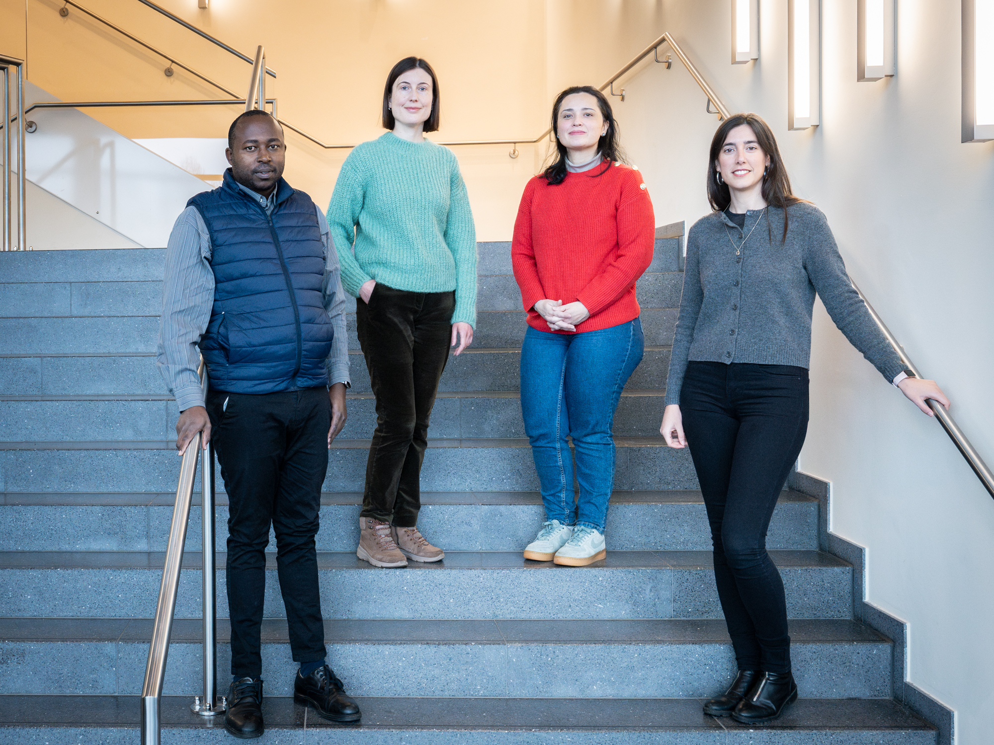 Four young people stand in a semicircle on a staircase.