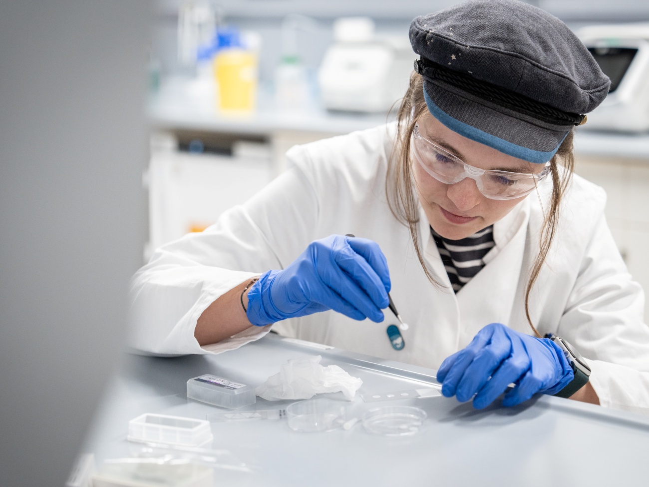 In a laboratory, a young woman places a liquid on a slide.