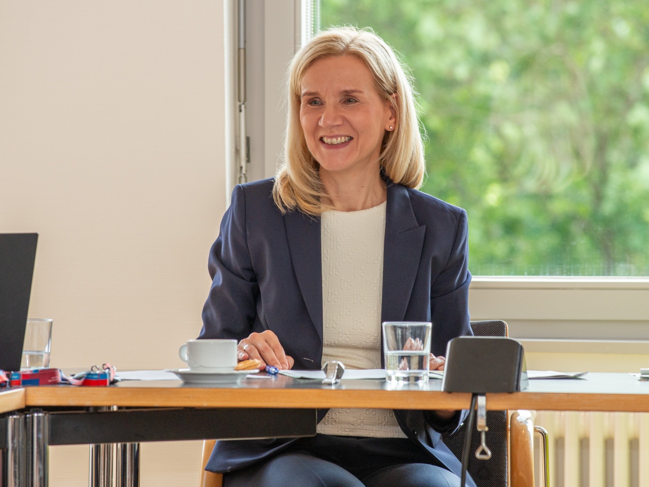 A woman is sitting at a table and smiling.
