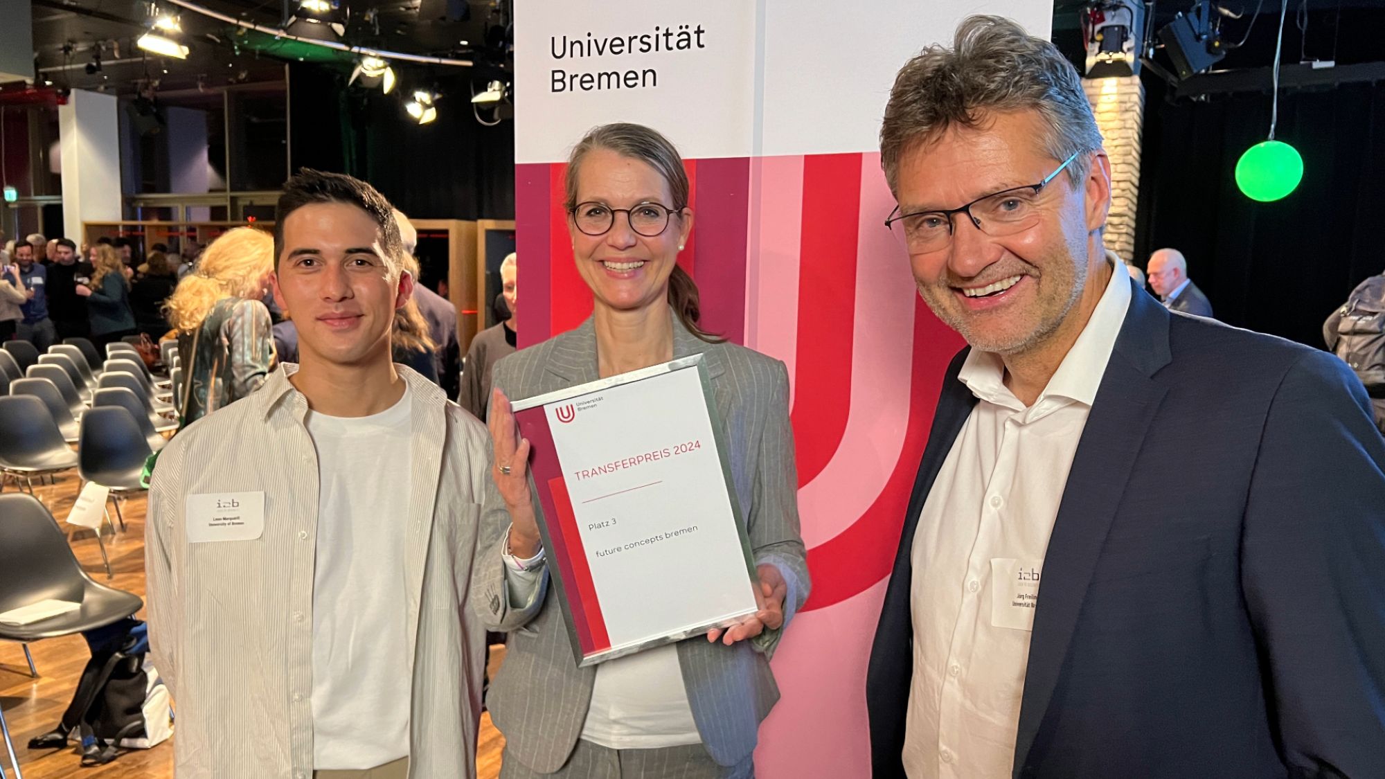 Three people smiling into the camera and showing a certificate.