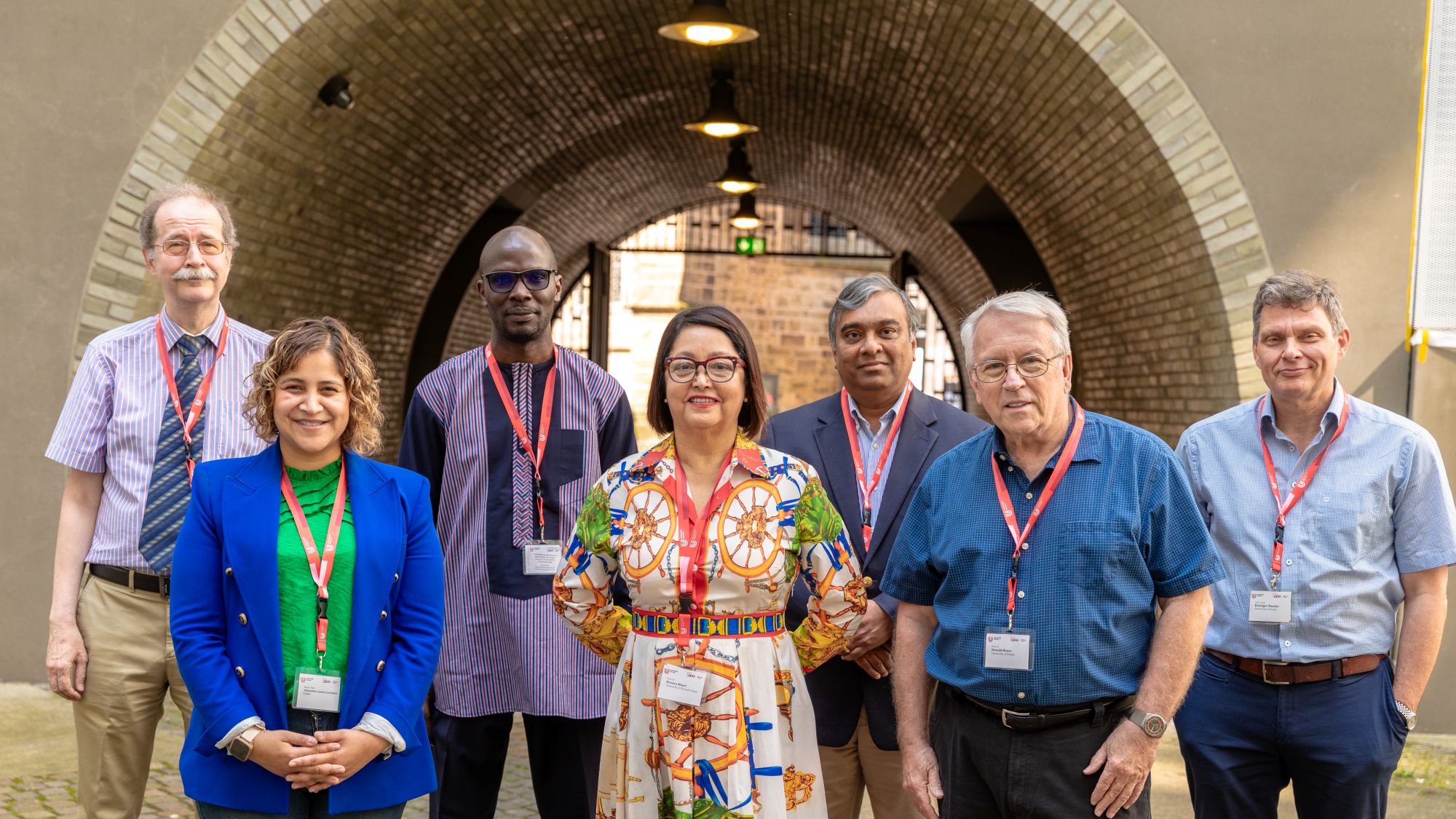 A group of people are standing in front of an archway and are smiling at the camera.