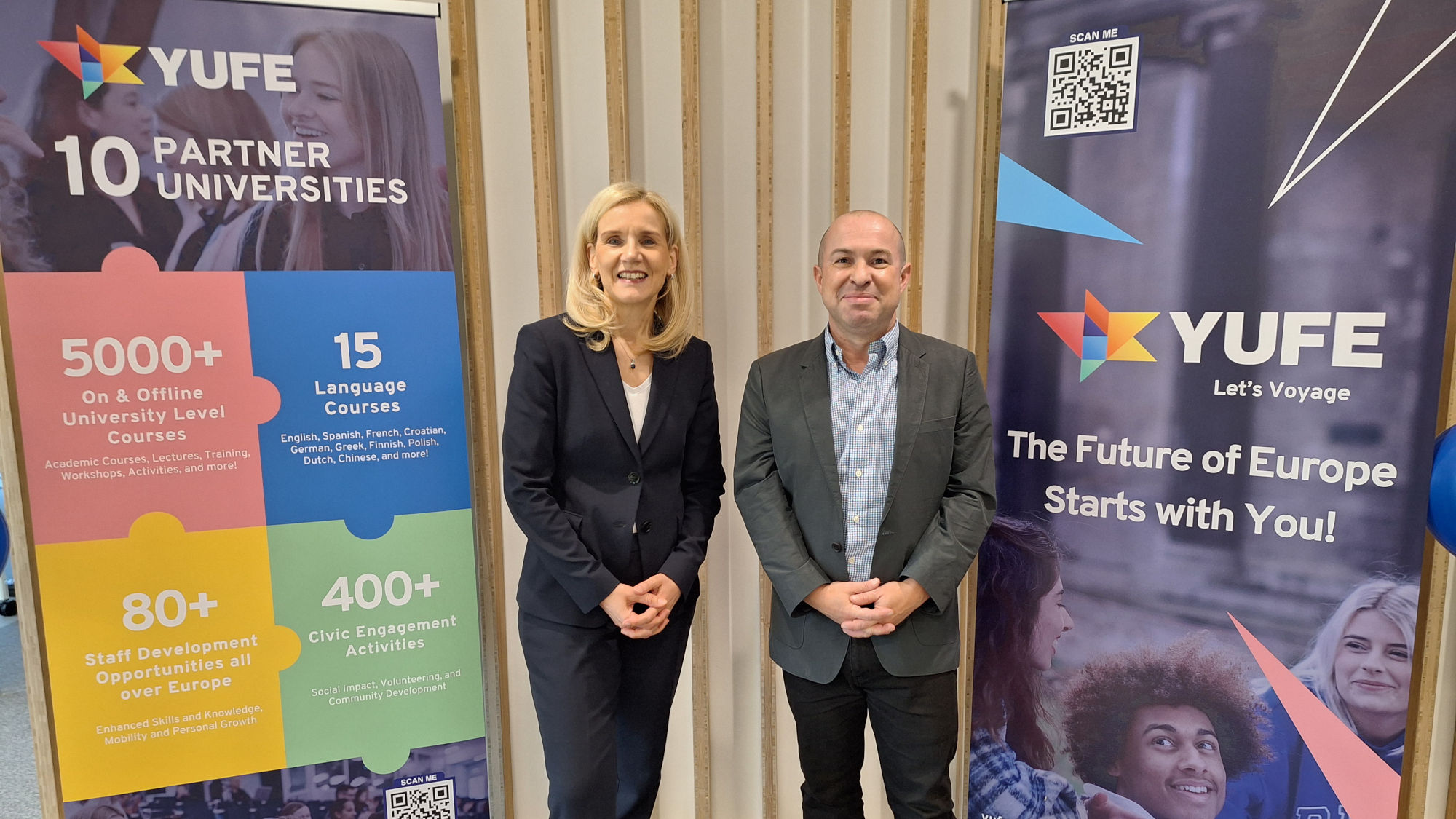 Jutta Günther and Daniel Mouchard stand between two large YUFE posters.