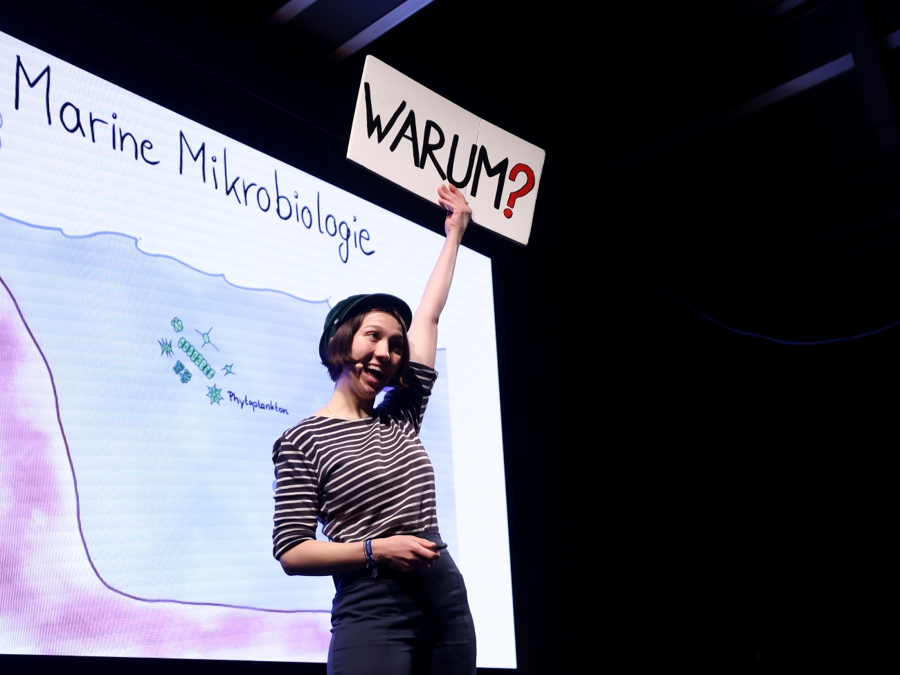 A woman holds up a sign with the question “why?”