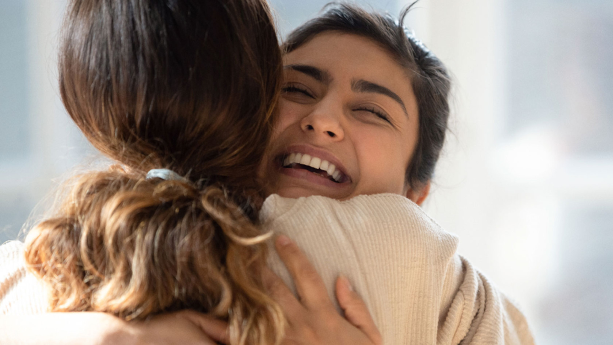 Two young women embrace each other affectionately