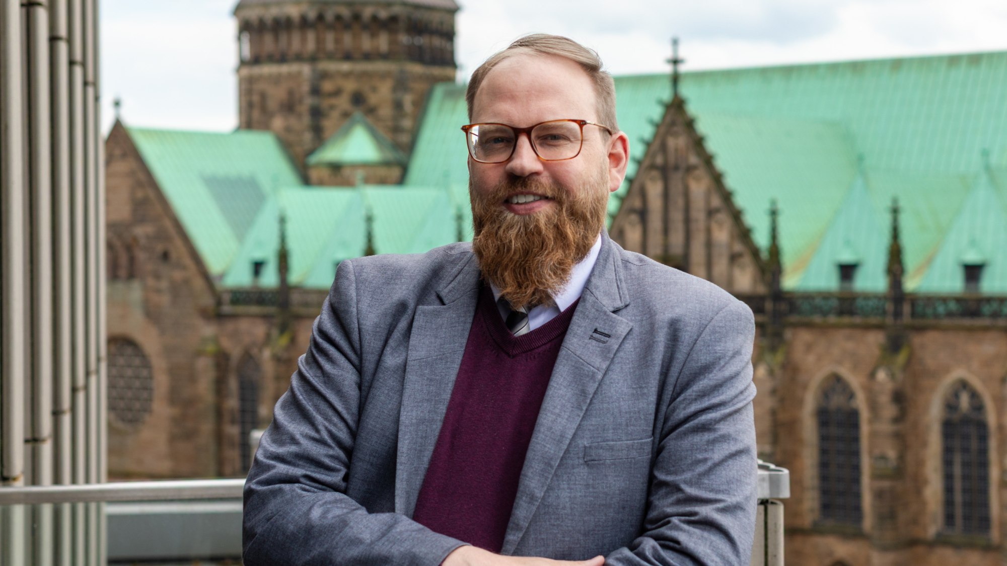 Eine Person lächelt in die Kamera. Im Hintergrund ist der Bremer Dom zu sehen.
