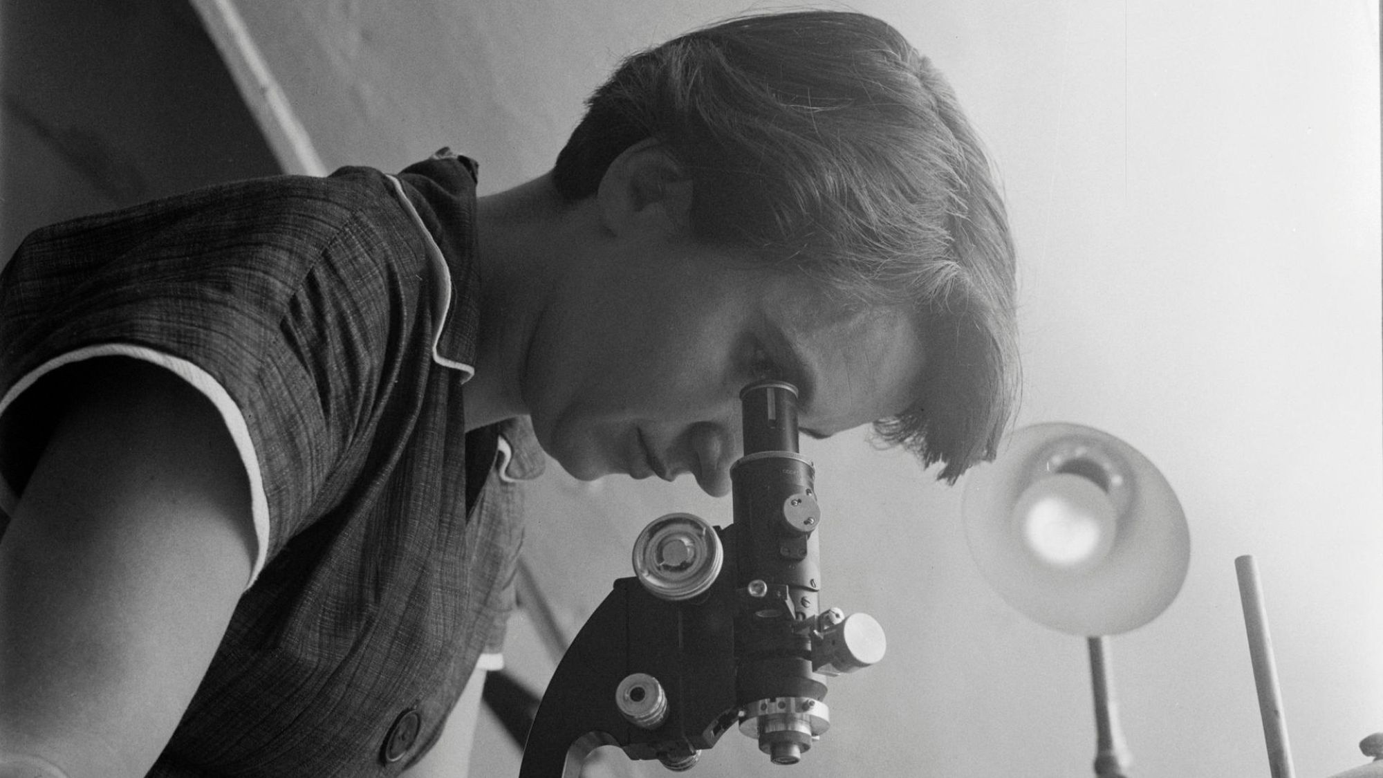 A woman looks through a microscope.