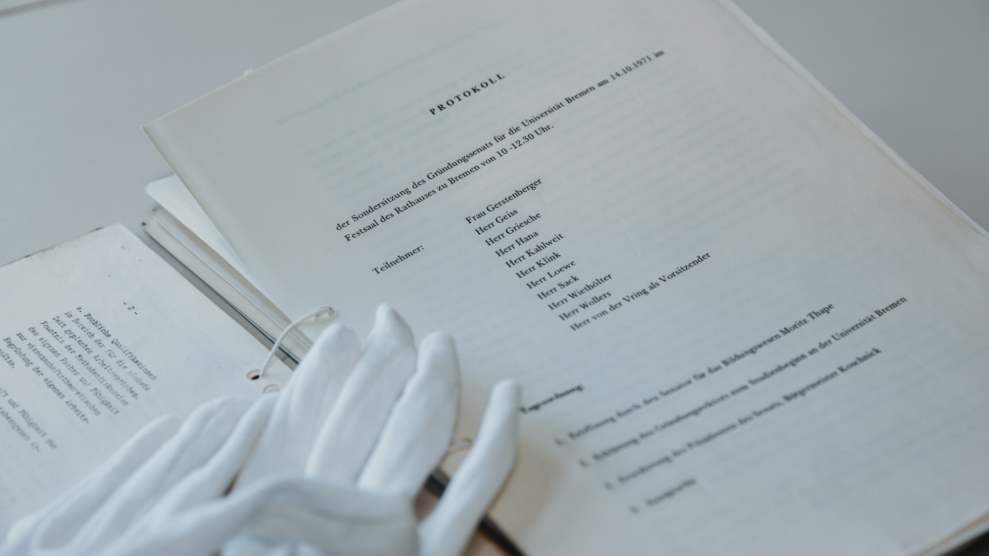 Two white gloves lie on old paper protocols.